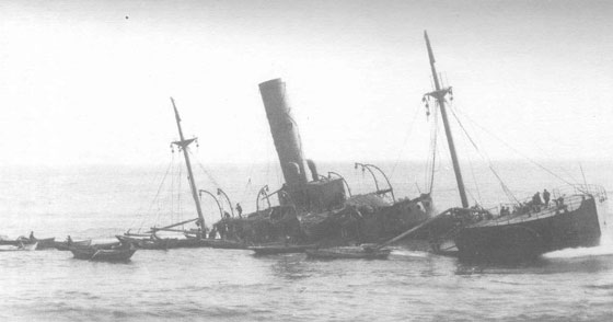 The S.S Florizel, aground and breaking up off Cappahayden Head, Southern Shore, Newfoundland.  Here, the stern of the vessel is settled in the water. Dories, like those used to rescue survivors, wait alongside while salvagers search for anything of value - Le S.S Florizel, chou et se cassant vers le haut de outre de la tte de Cappahayden, rivage mridional, Newfoundland. Ici, la poupe du navire est arrange dans l'eau. Les petits bateaux, comme ceux employs pour sauver des survivants, attendent bord  bord tandis que les programmes de sauvetage recherchent n'importe quoi de valeur
