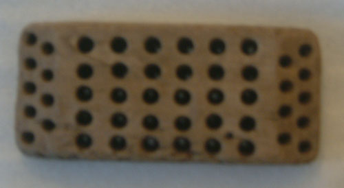 Wooden back from a scrub brush.  Brush-wire fasteners remain, but the bristles have loosened and become lost during its stay underwater.  From shipwreck in Trinity Harbour - La brosse en bois, brins se sont desserres et deviennent perdue pendant son sjour sous-marin. Du naufrage dans le port de Trinity