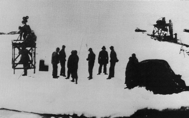 Poduction crew on the ice. Camera on the left and operational equipment on the right side, and the additional material under the cover of protection in the foreground. - Ouvriers sur la glace. Appareil-photo sur l'quipement gauche et sain du ct droit, et le matriel supplmentaire sous la bche de protection dans le premier plan