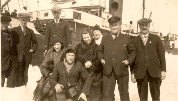 Seven men and two women standing near the rescue ship  S.S. "Sagona." - Sept hommes et deux femmes se tenant prs du S.S. "Sagona."