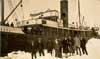 Seven men and two women standing near the rescue ship  S.S. "Sagona." - Sept hommes et deux femmes se tenant prs du S.S. "Sagona."